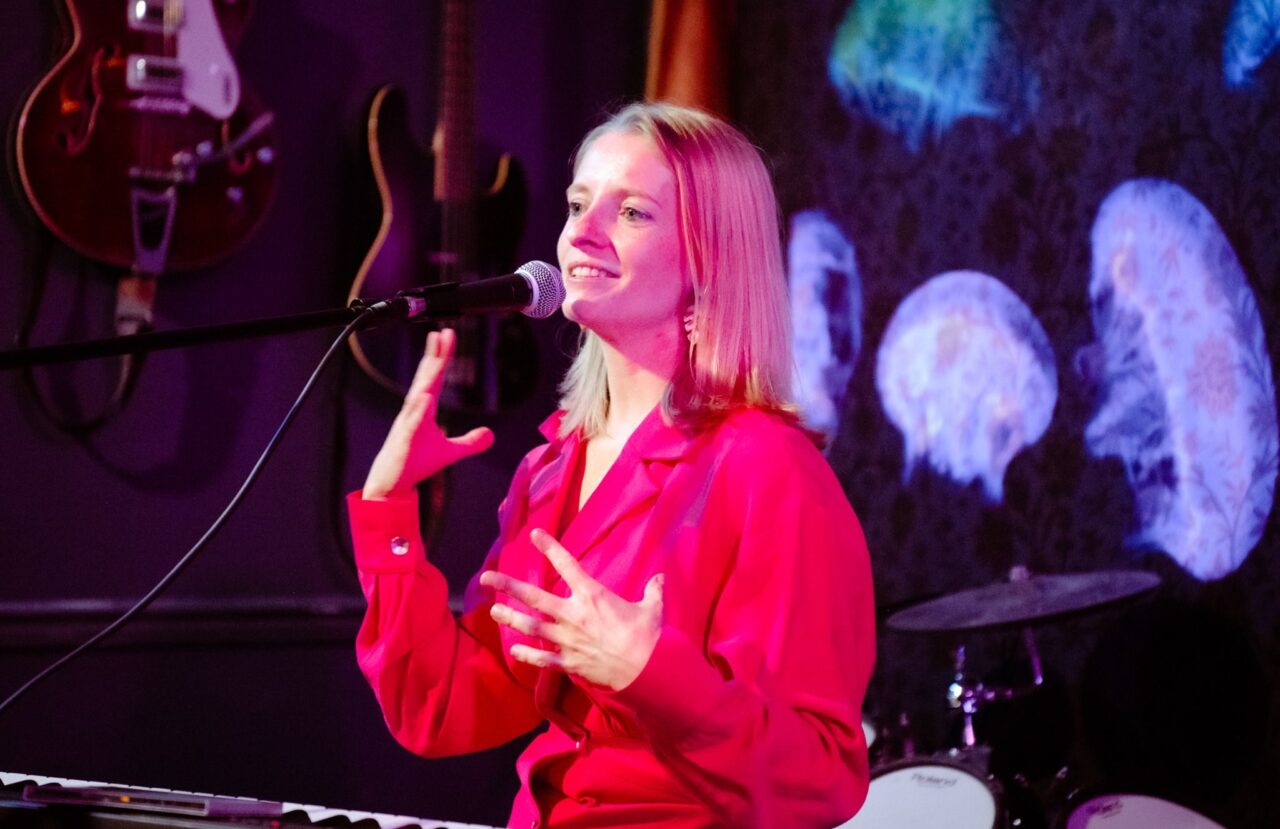 Marieke zingt op een podium in New York.